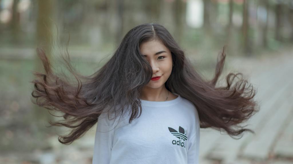 Woman With Long Hair Waving on Air and Wearing White Adidas Shirt